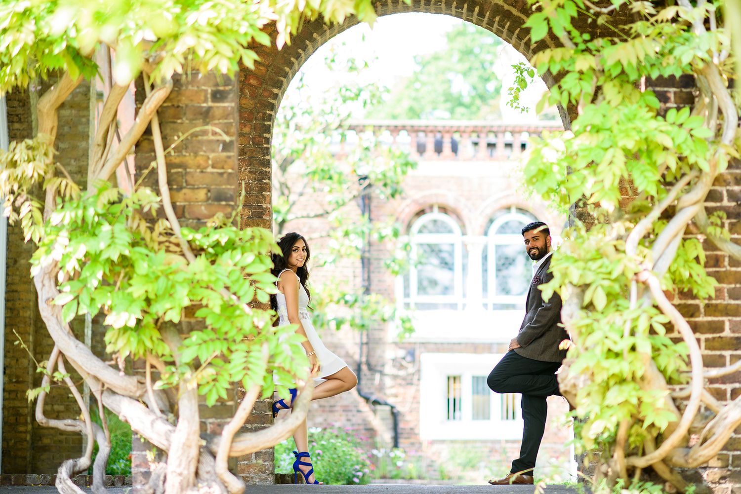 Romantic garden photoshoot near brick archways and green foliage.
