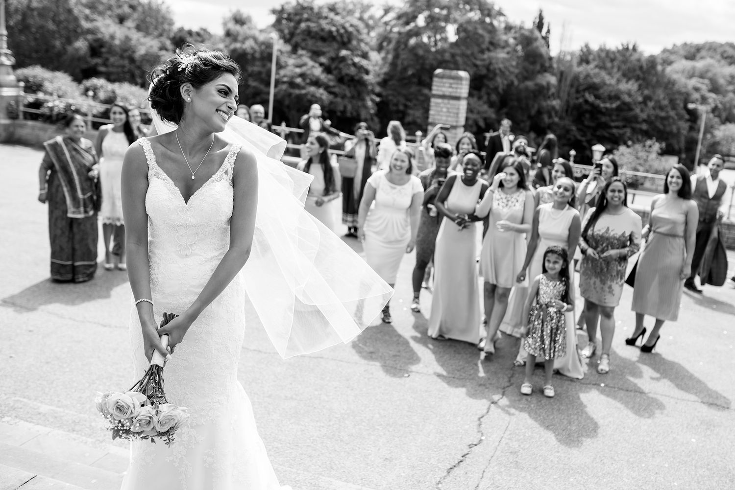 Panoramic black and white shot of wedding celebration with guests lined up outside.