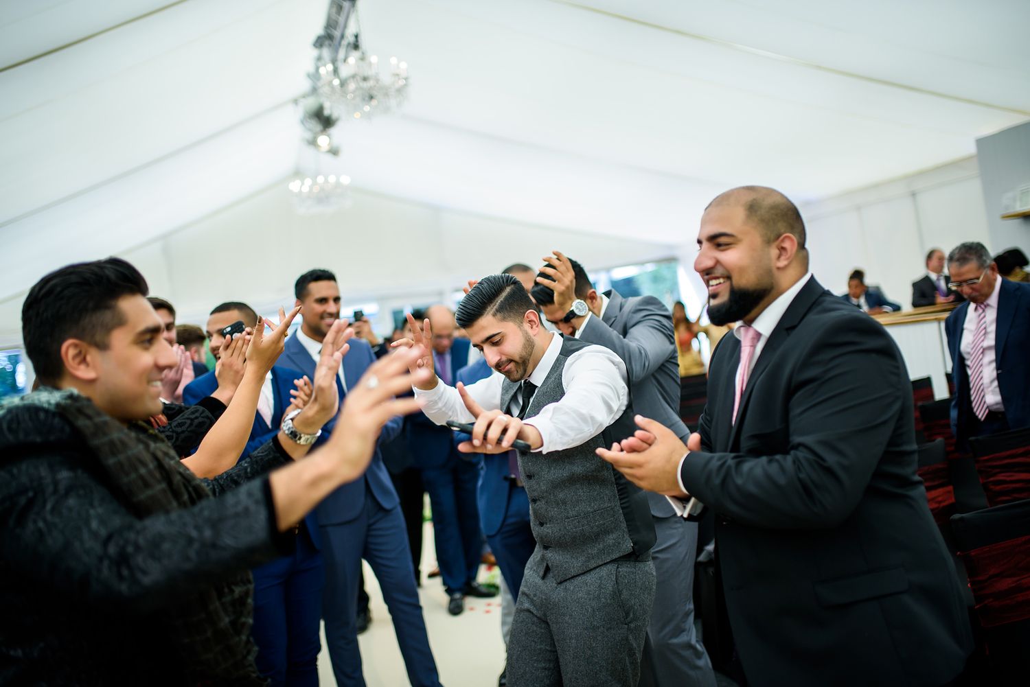 Wedding reception guests dancing and celebrating in an indoor venue.