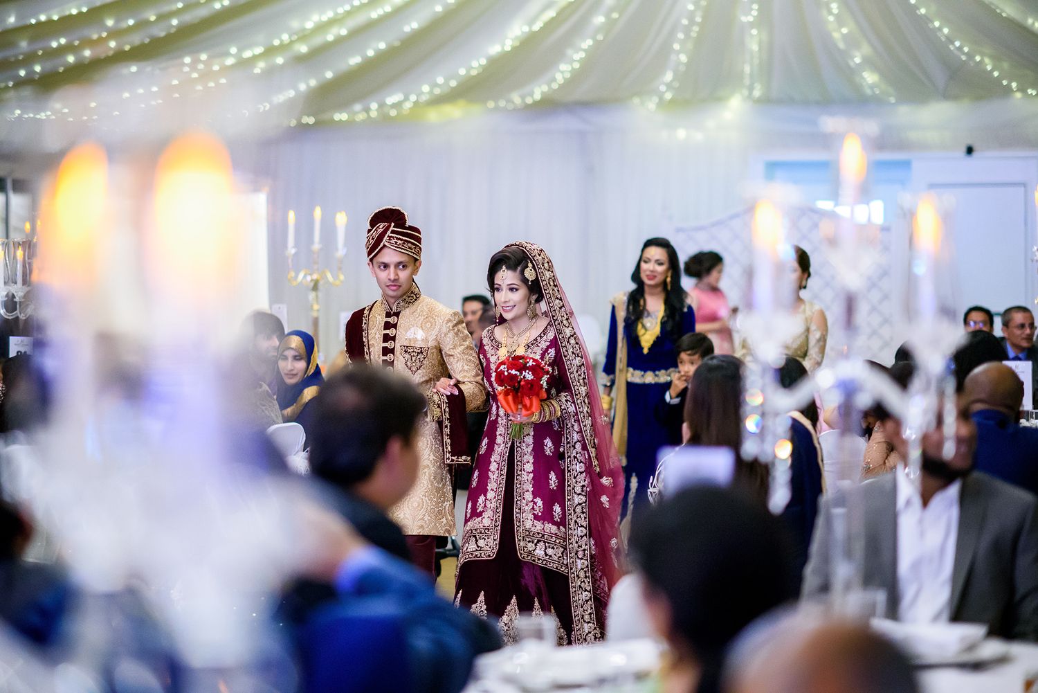 Wedding celebration in a beautifully lit reception hall with hanging decorative lights.