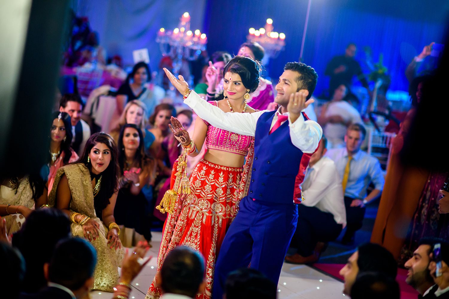 Wedding reception dance floor filled with guests under dramatic blue lighting and decorations.
