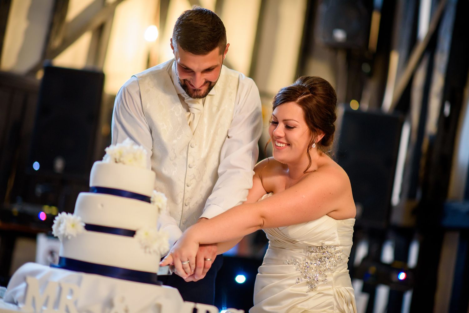The newlyweds share a laugh while cutting their three-tiered wedding cake together.