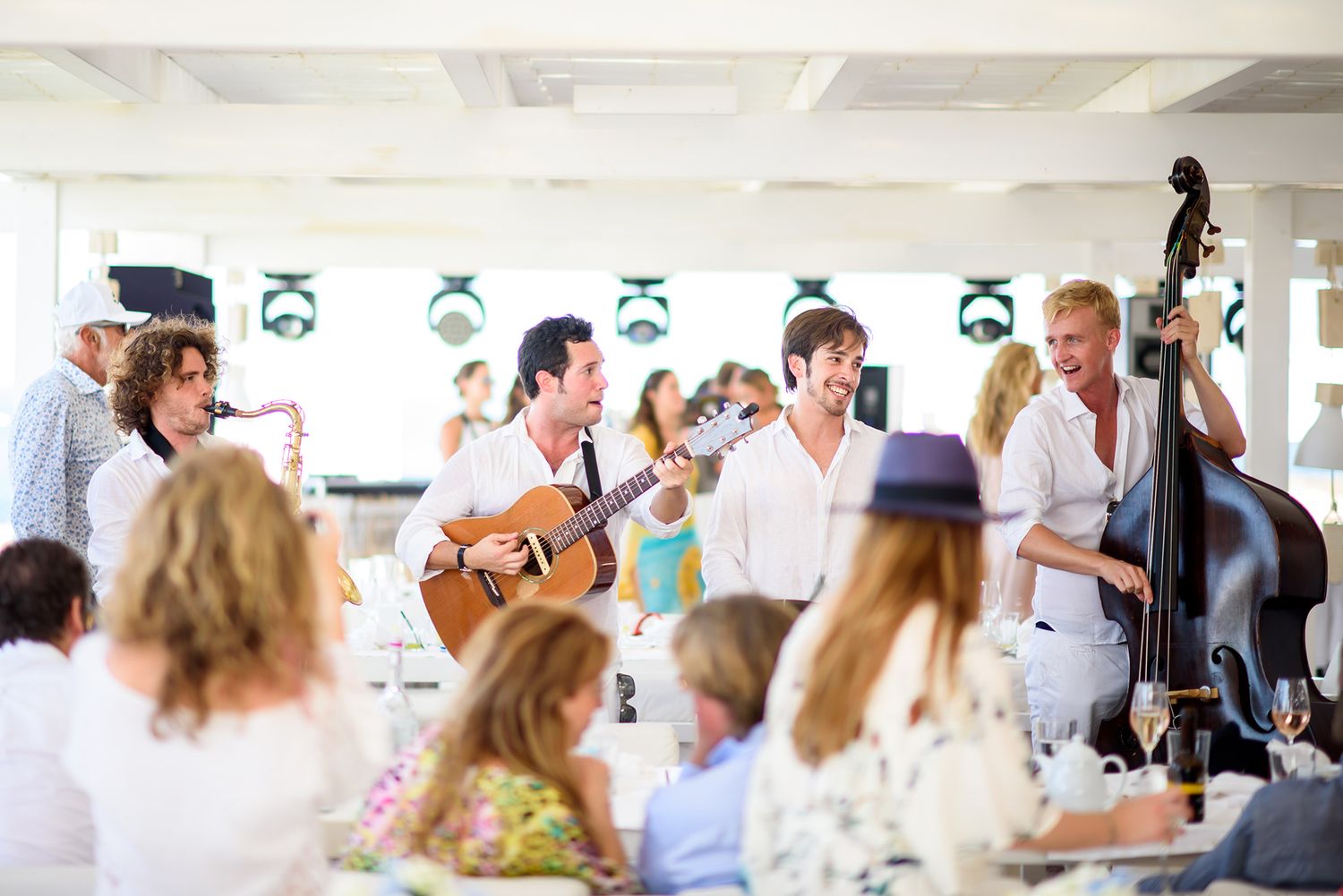 Elegant reception tables set with white linens and floral centerpieces under a tent canopy.