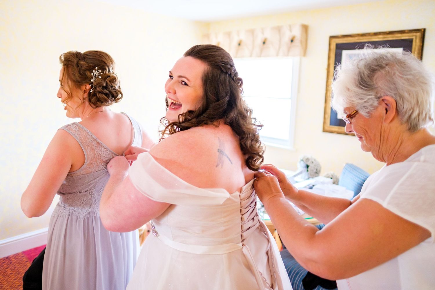 Wedding preparations showing dress fitting and final touches in a bright white room.
