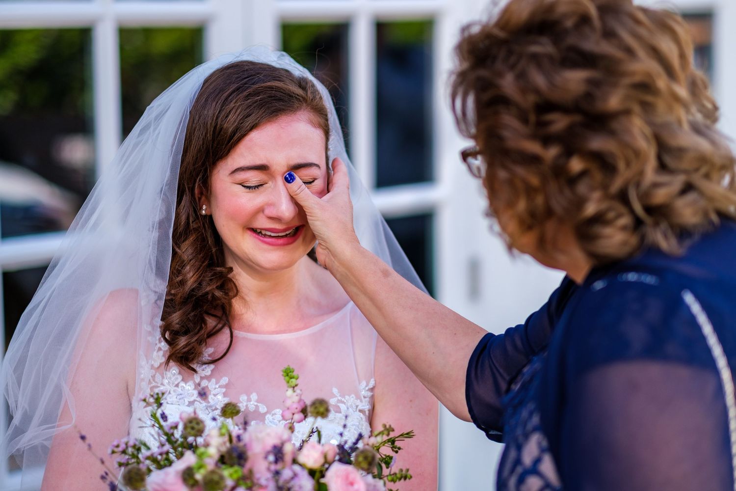 Wedding party sharing emotional laughter and embraces during outdoor celebration.