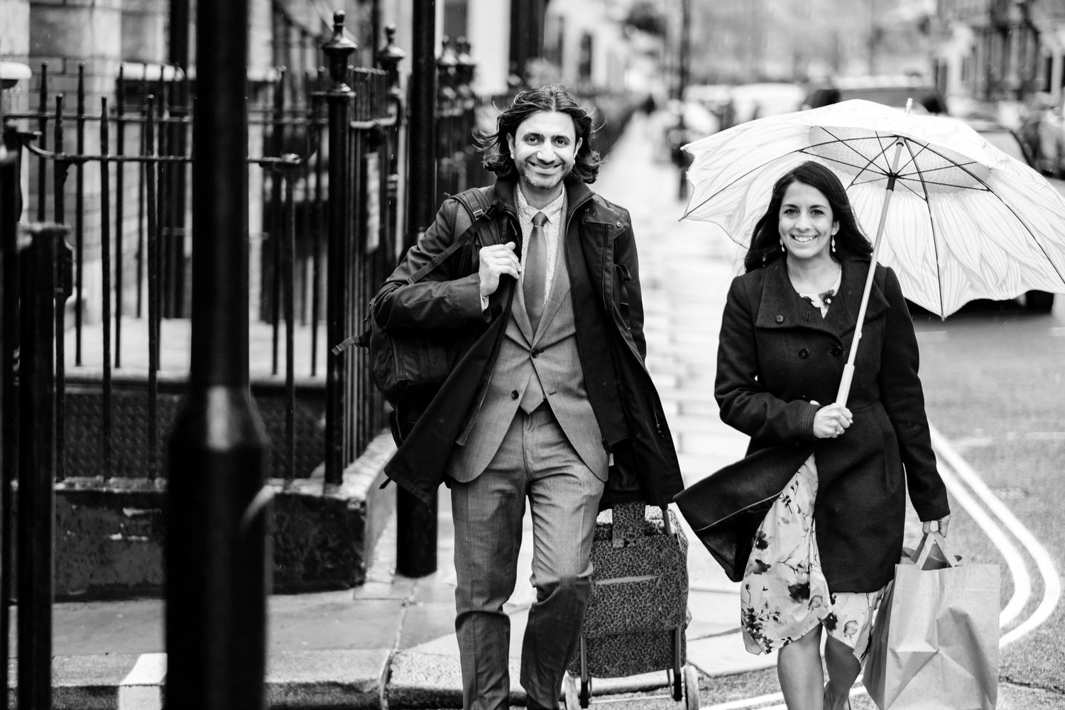 A couple running together in the rain on a city street, sharing joyful expressions under an umbrella.