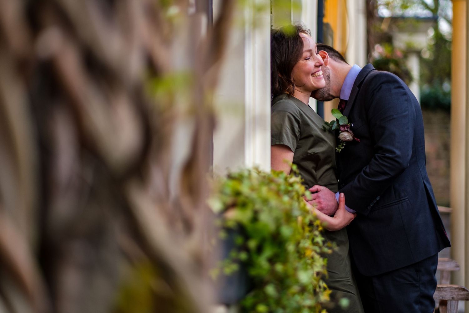Intimate celebration captured between trees and stone walls in garden setting.
