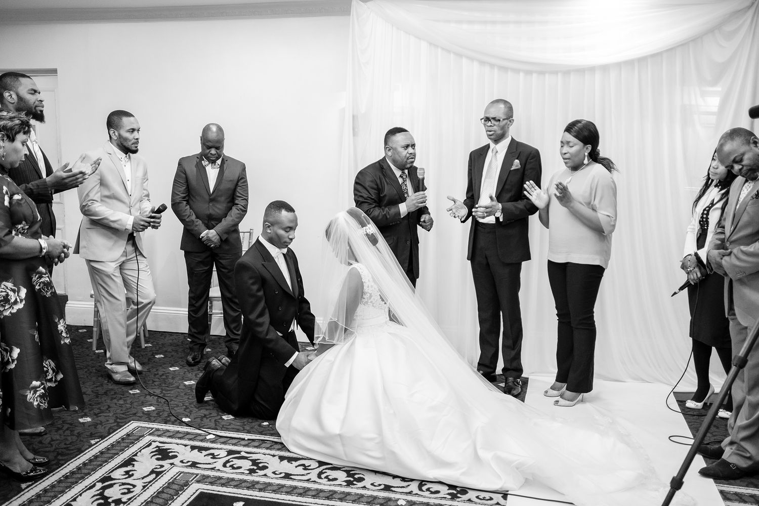Wedding guests witness an intimate ceremony in an elegant white-draped venue.