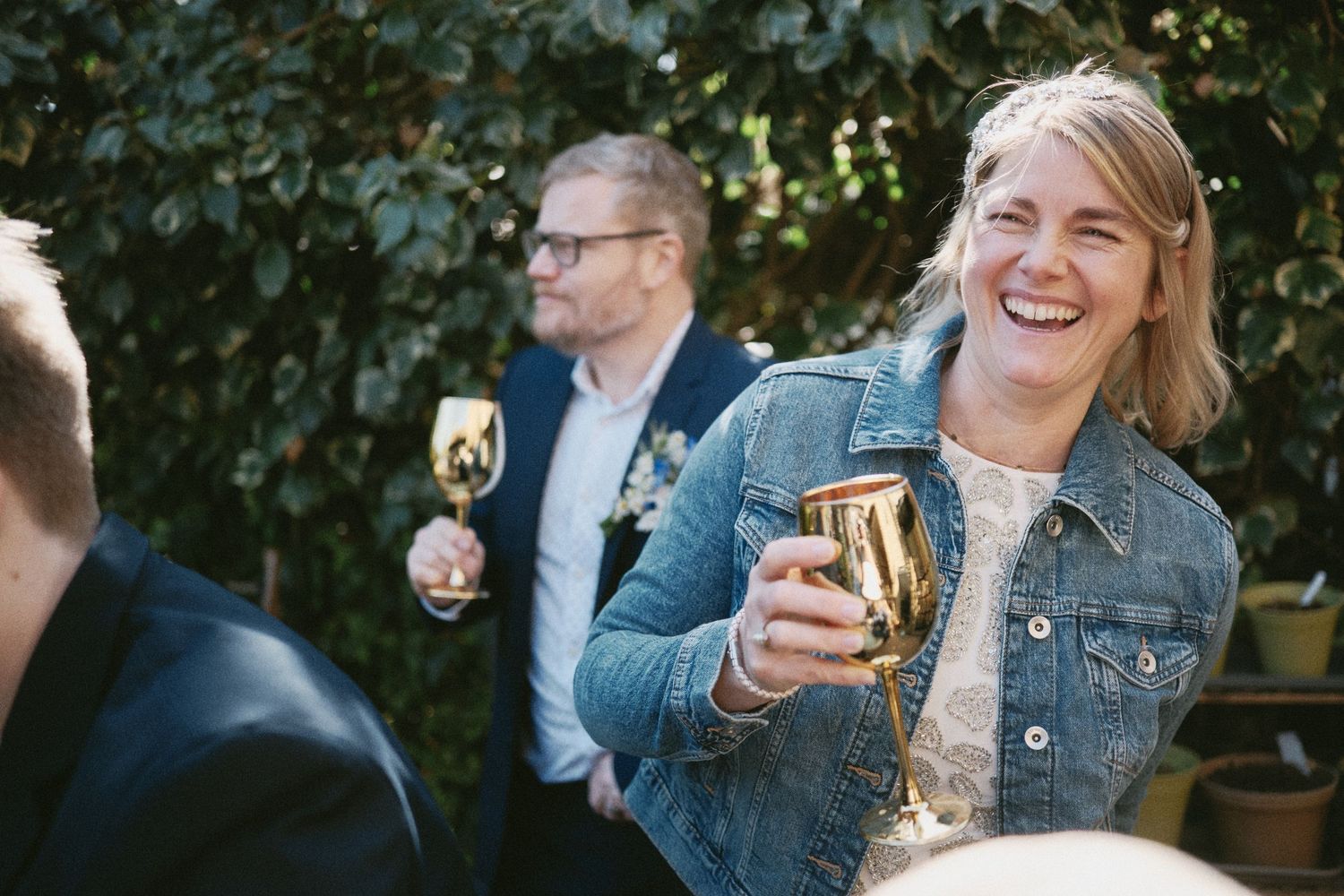 Wedding celebration outdoors with guests enjoying drinks and laughter.