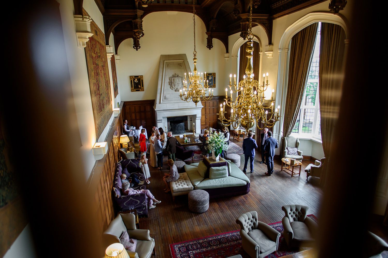 Elegant reception room with chandelier and fireplace viewed through doorway during wedding celebration.