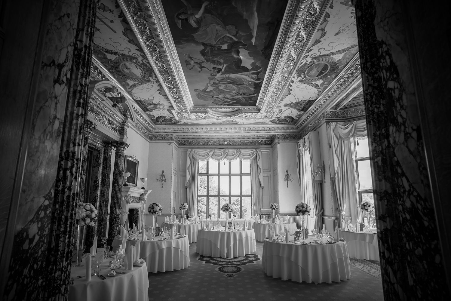 Black and white panoramic view of an elegant ballroom with ornate architectural details.