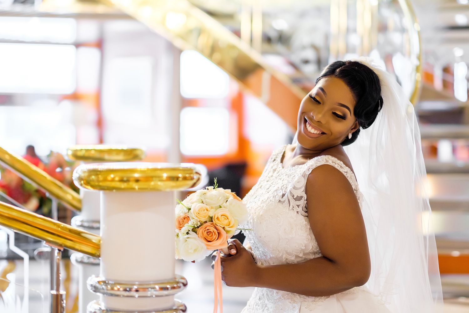 Joyful bride in white lace dress holding peach bouquet.