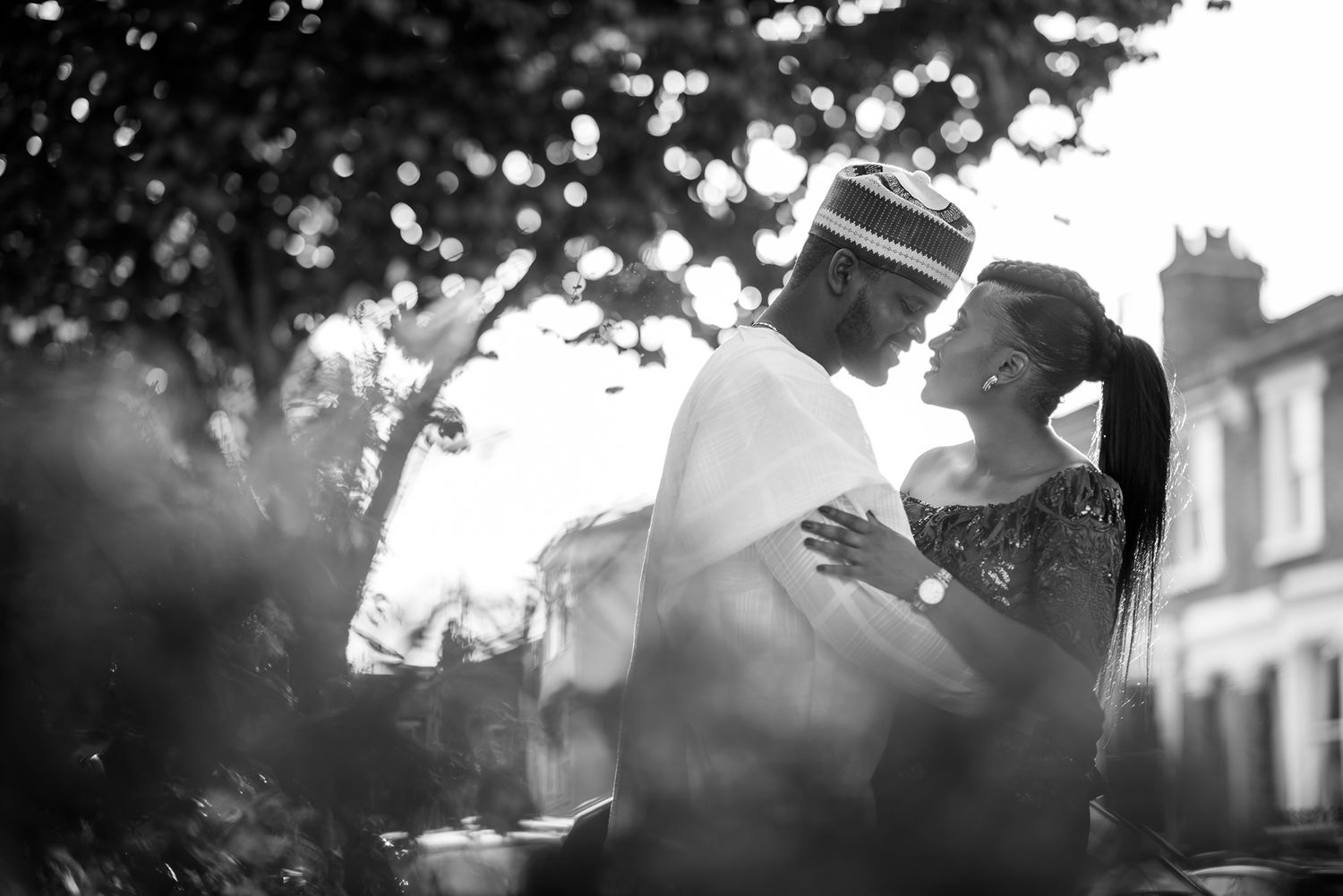 Black and white silhouettes capture a romantic couple's embrace under natural lighting.