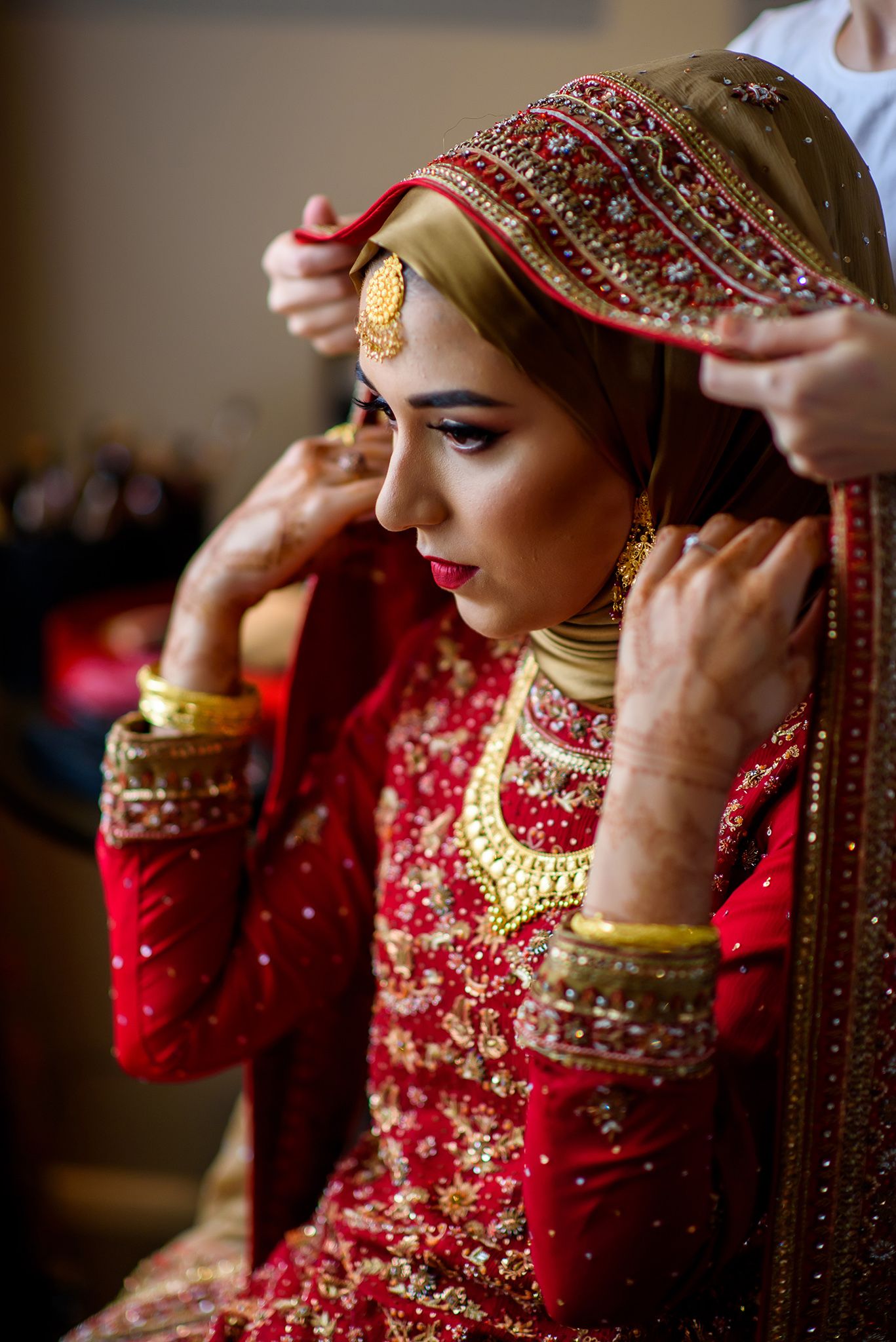 Close-up shots of traditional Indian bridal jewelry and bangles being placed on wrists in a red and gold attire.