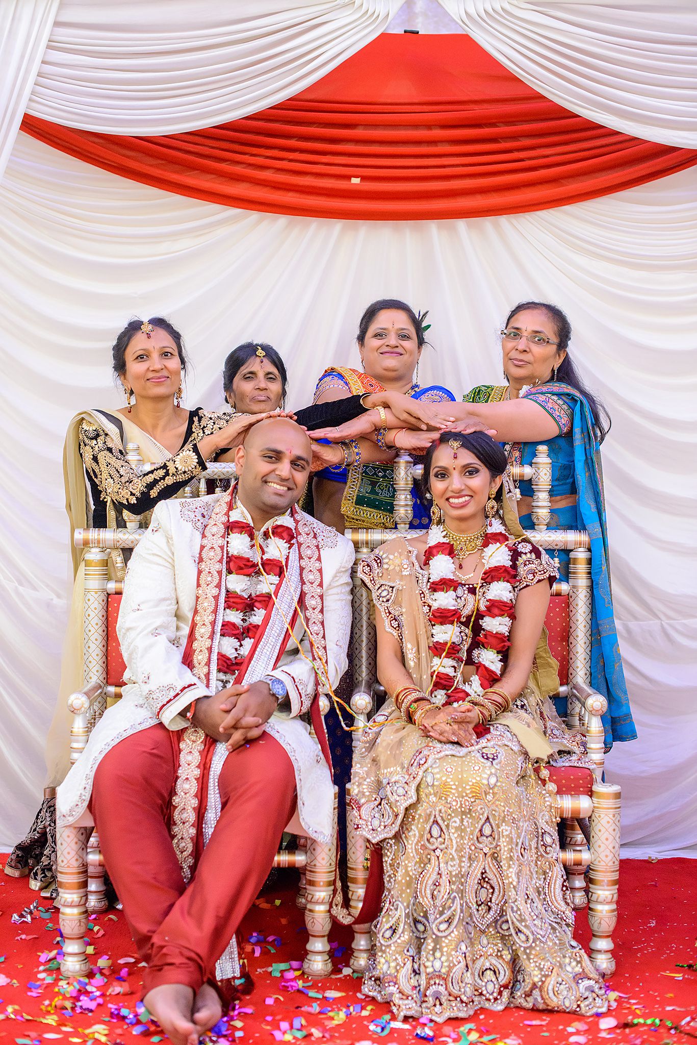 Wedding ceremony seating with red and white draped backdrop and decorative chairs.