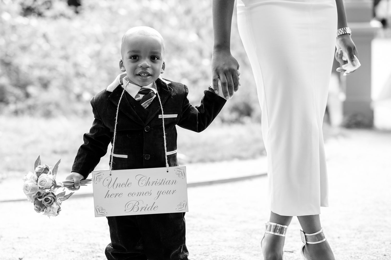 Young attendants in formal wear make their way down an outdoor wedding aisle.
