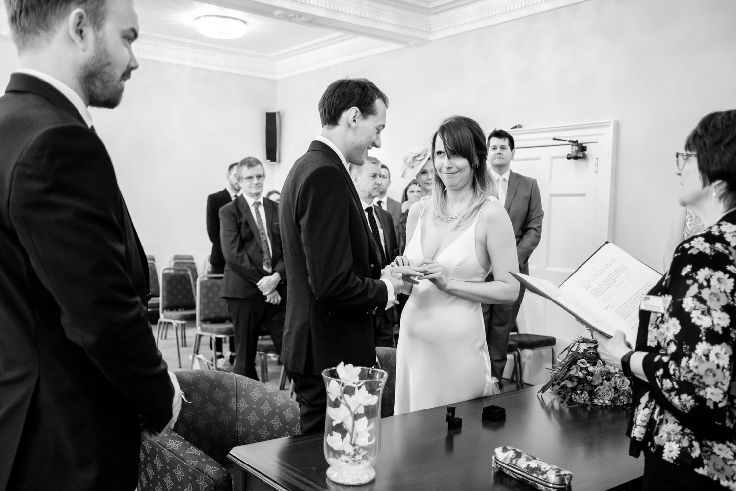 Light-filled reception room with wedding guests and floral arrangements.