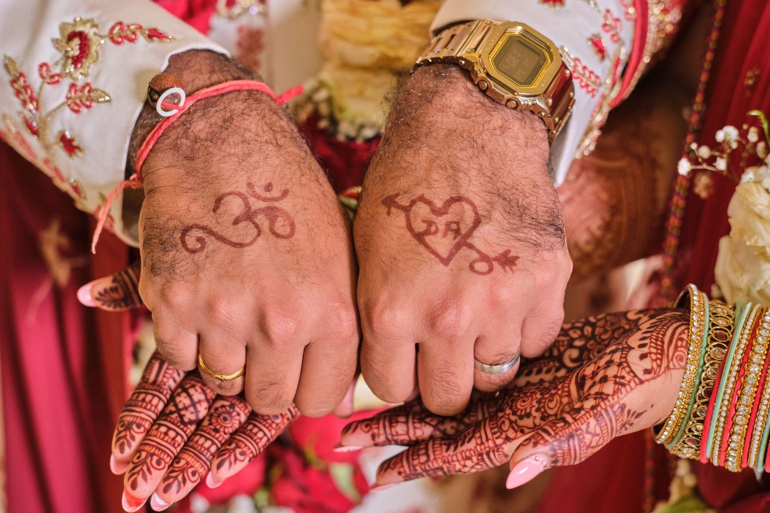 Close-up detail of hands with intricate henna designs and wedding jewelry during an Indian ceremony.