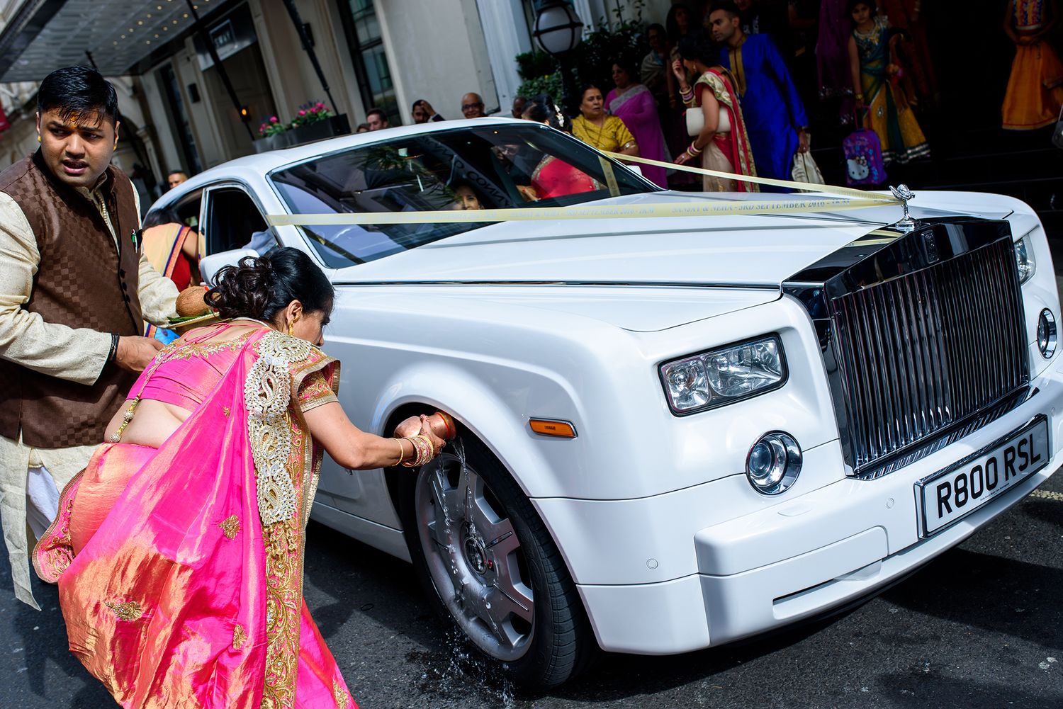 White Rolls Royce luxury wedding car decorated with floral arrangements.