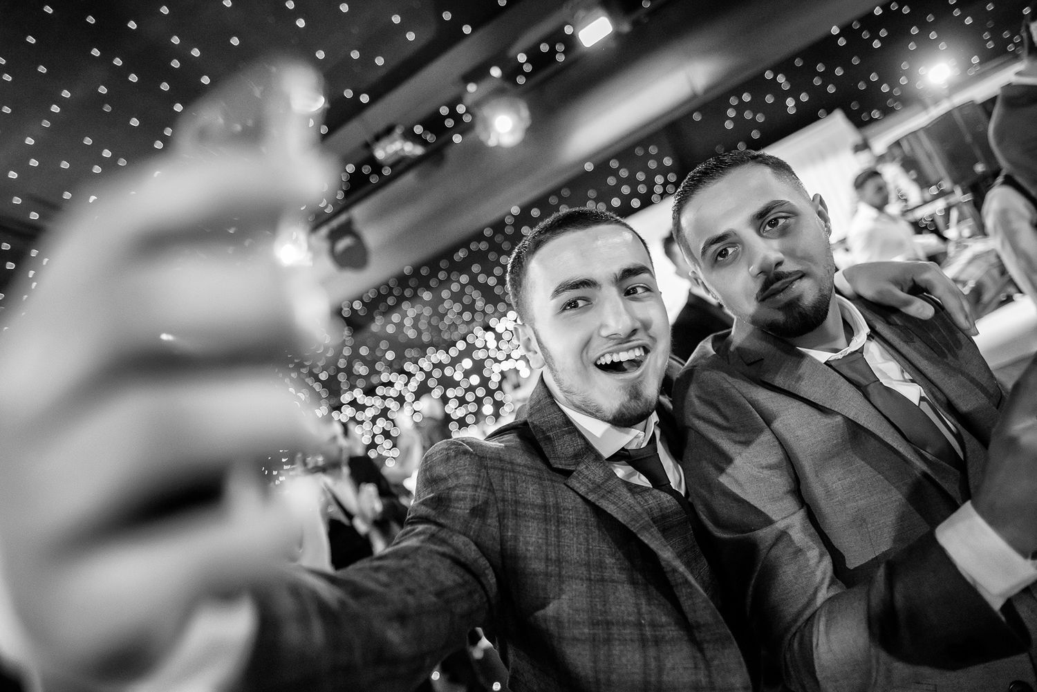 Party guests celebrating beneath starry lights and chandeliers at an elegant evening event.
