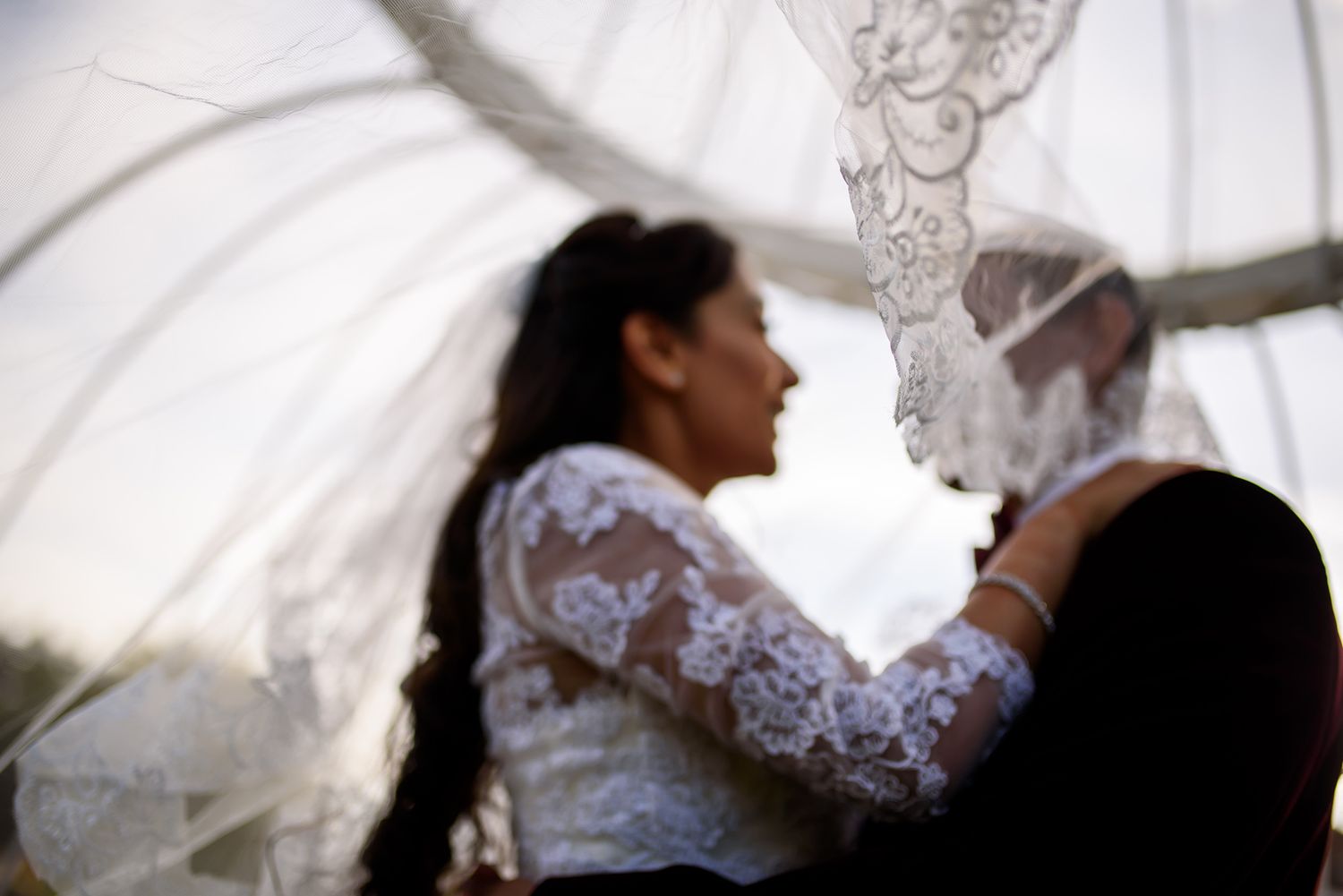 Elegant white lace wedding dress details against soft background.