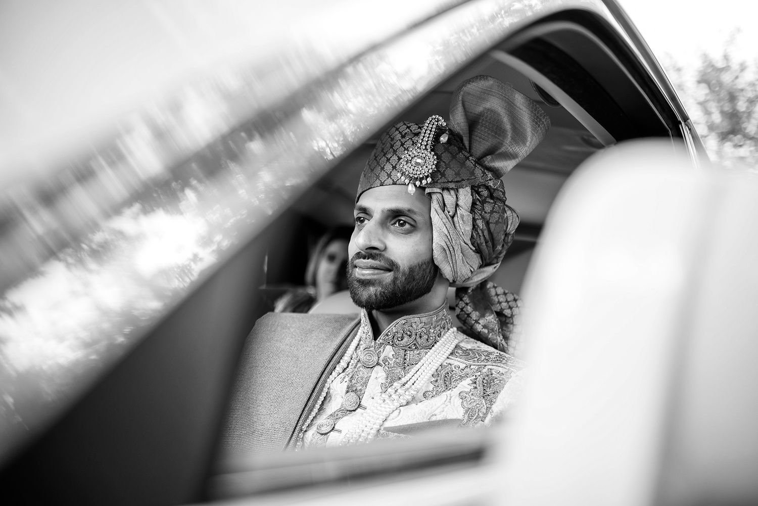 Artistic black and white shot through car window during wedding celebration.