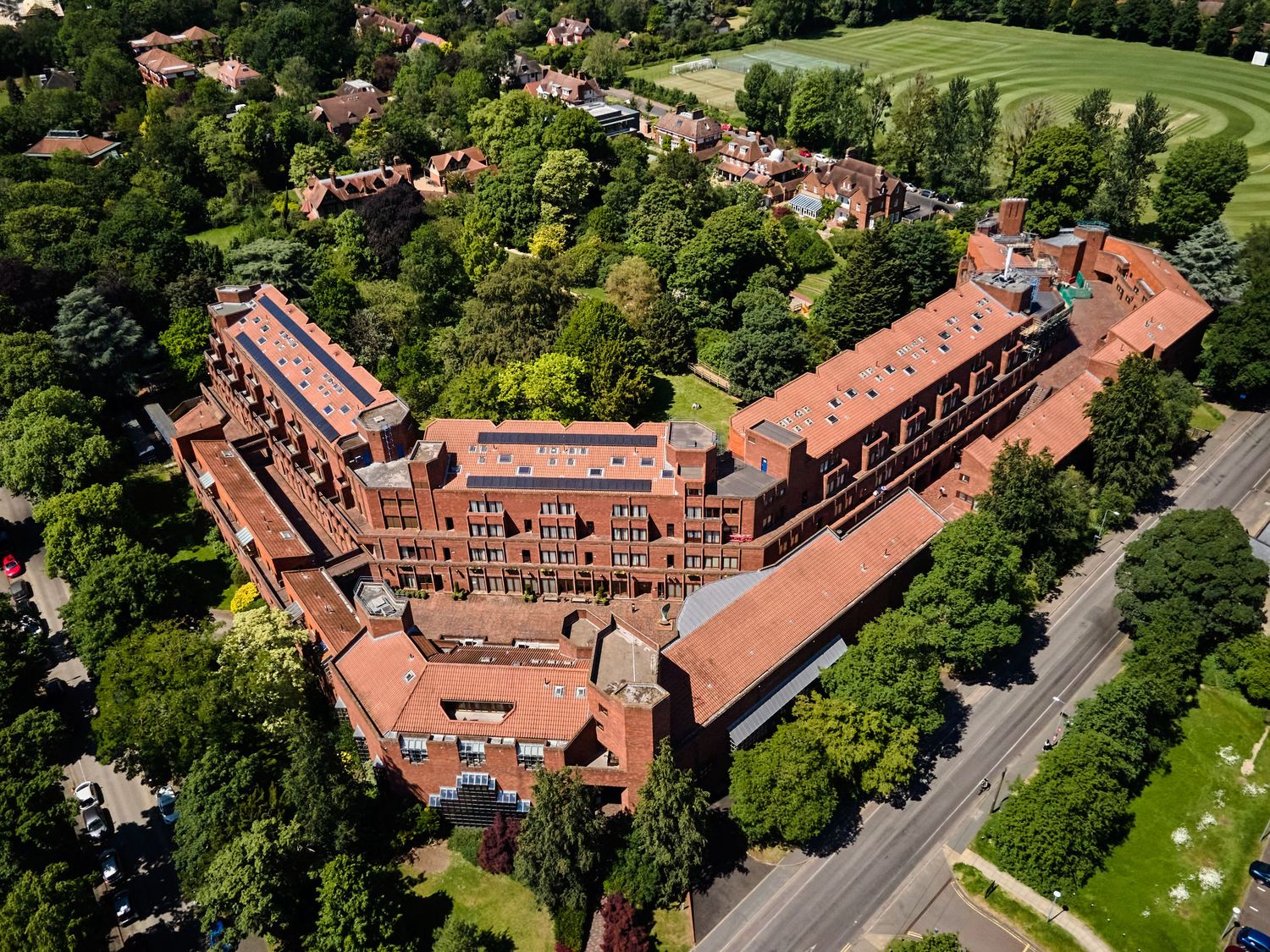 Aerial view of red brick mansion buildings surrounded by manicured gardens and trees.