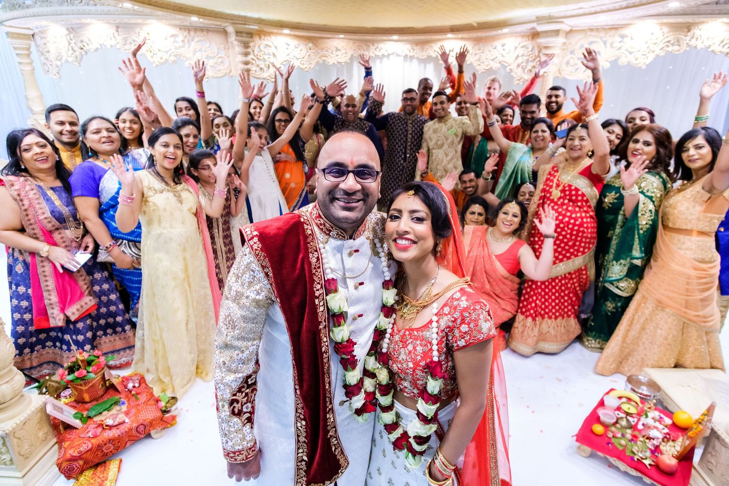 Joyful celebration scenes from an Indian wedding with guests dancing and posing in colorful traditional outfits.