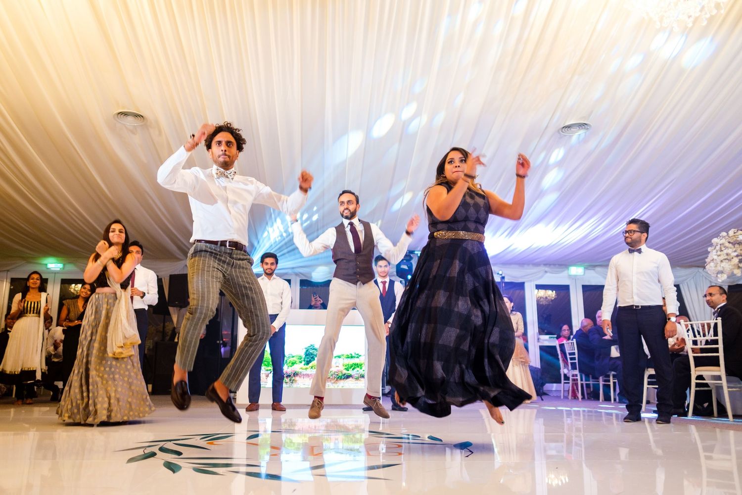 Wedding guests dance and celebrate together on an illuminated dance floor at an elegant reception venue.