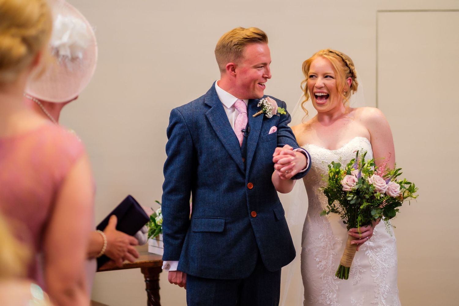 A couple sharing a joyful moment during their wedding celebration with floral bouquet.