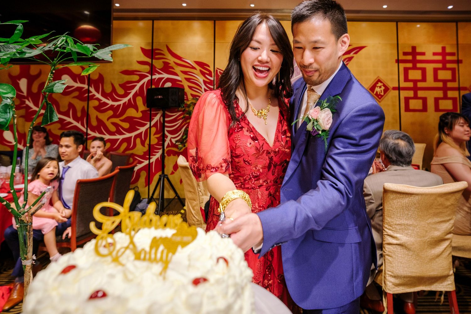 Wedding celebration with guests enjoying festivities in a room with traditional Chinese decor.