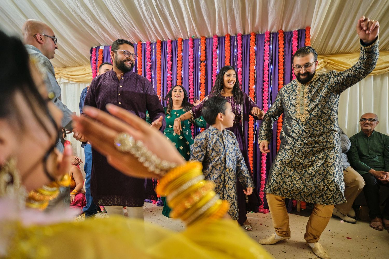 People dancing and enjoying festivities at a wedding celebration with vibrant decorations and colorful outfits.