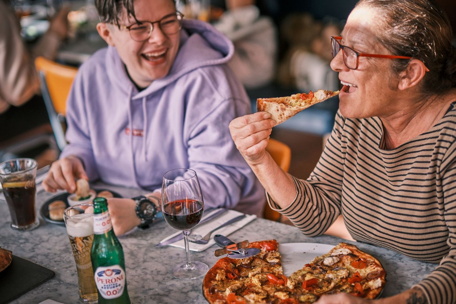Diners sharing pizza and conversation at casual restaurant table.