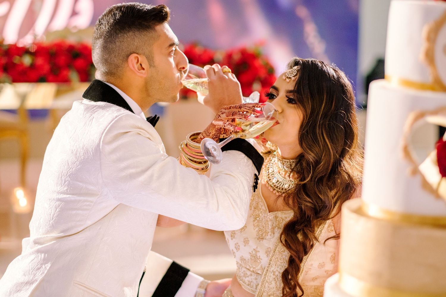 Romantic wedding cake cutting moment with elegant decor and lighting.