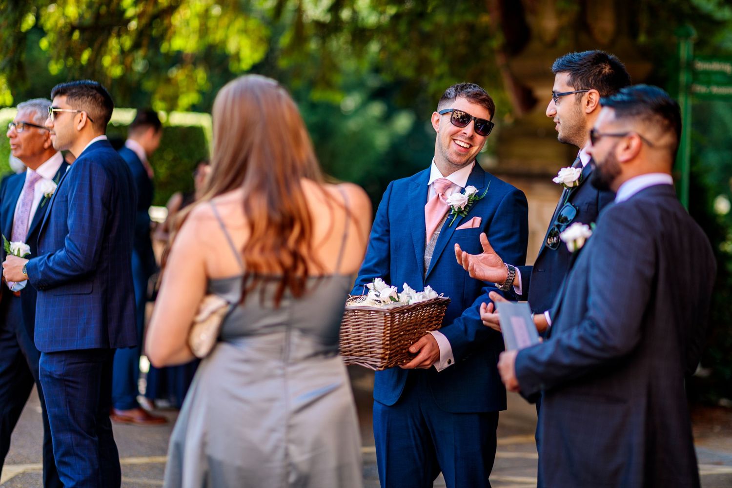 Wedding guests mingling and chatting during an outdoor cocktail reception in formal attire.