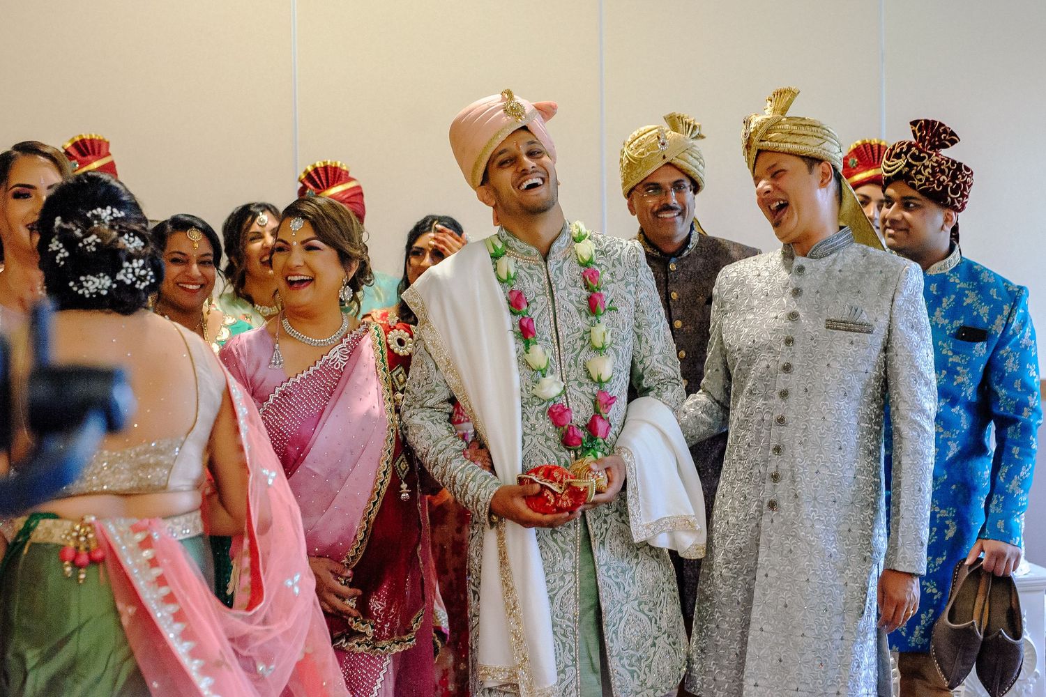 Guests in traditional Indian wedding attire gather for a celebratory group photo in colorful outfits.