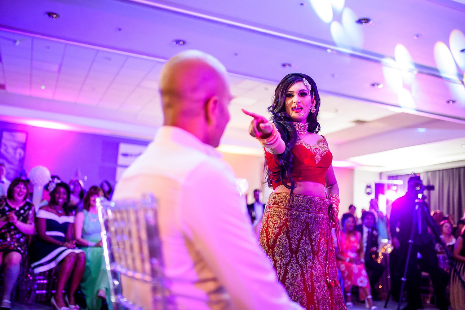 Purple-lit wedding reception venue with guests dancing and celebrating.
