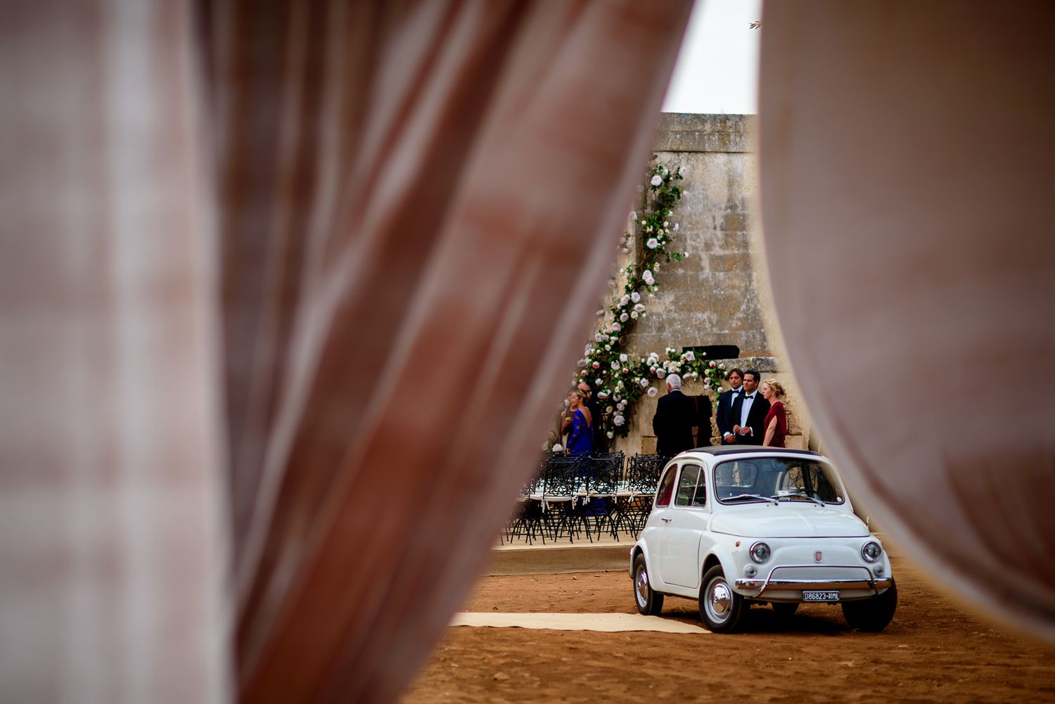 Vintage car viewed through elegant curtains at a wedding venue.