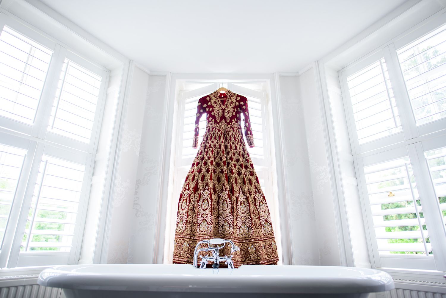 Bright sunlit room with bay windows and traditional dress displayed.