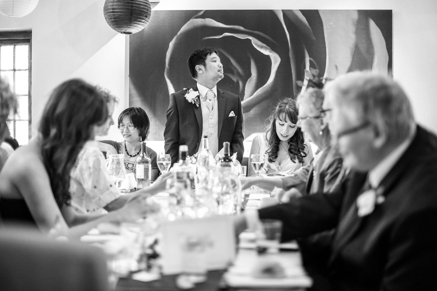 Black and white photo of wedding reception dinner with guests at round tables.