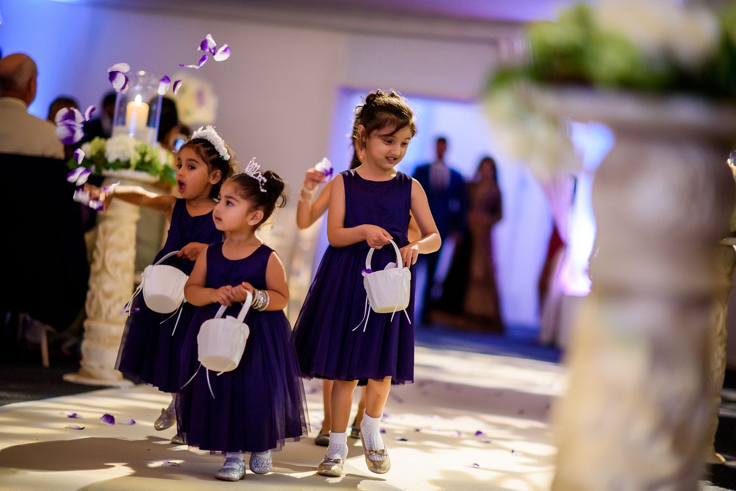 Reception venue decorated with elegant white drapes and purple lighting for an evening event.