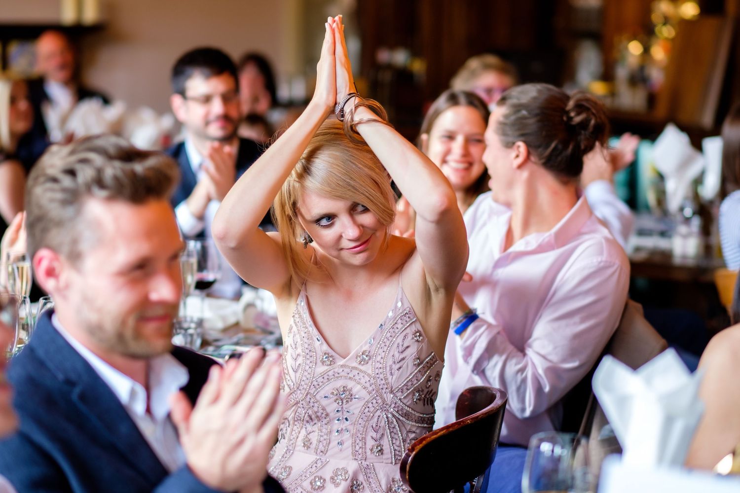 Wedding guest raises hands joyfully during reception celebration.