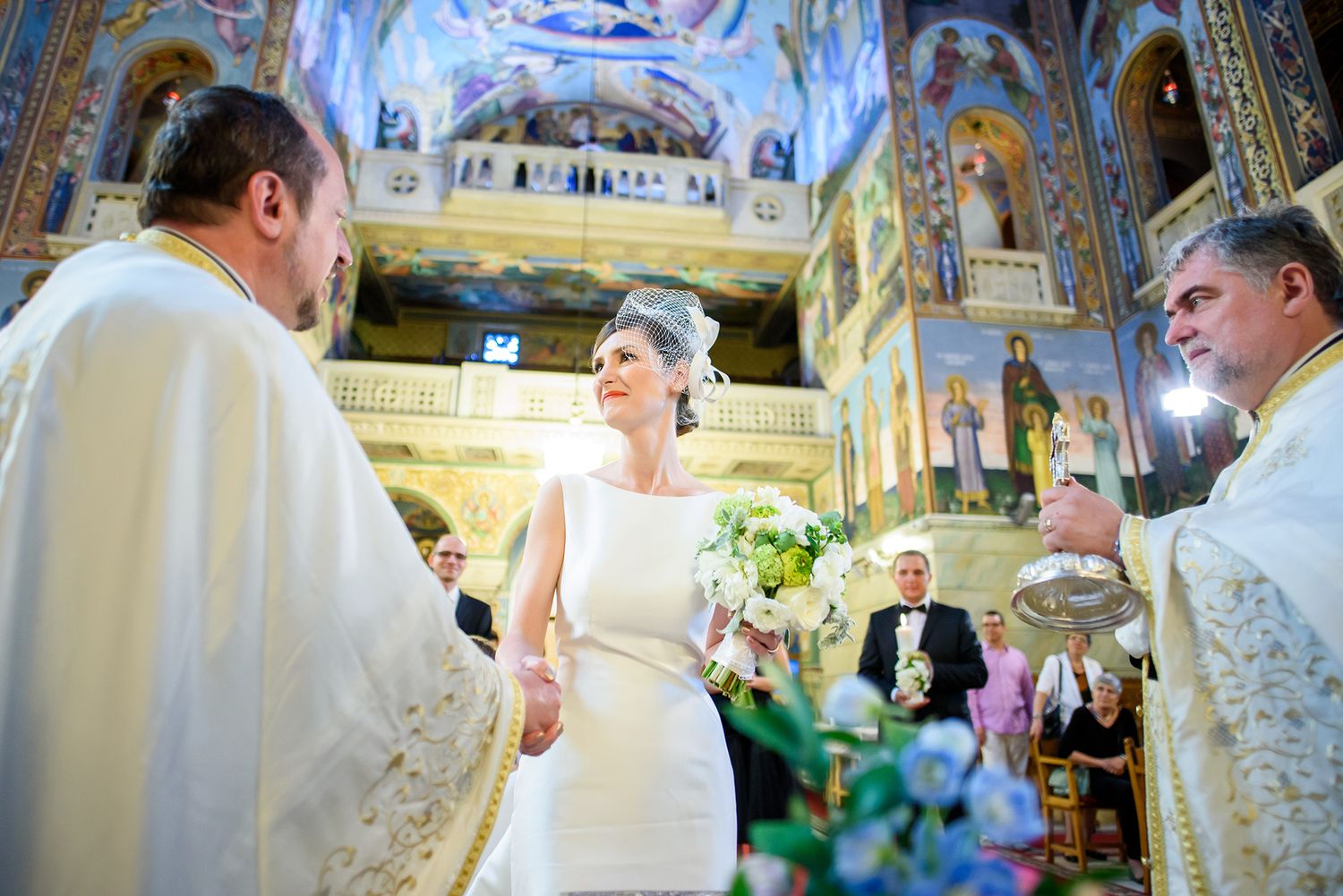 Traditional Orthodox church ceremony with elaborate ceiling frescoes and decorative details.