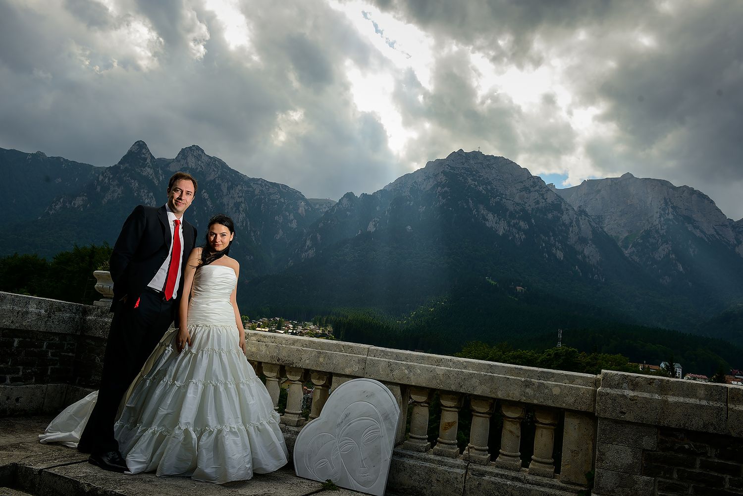 Wedding photography session against dramatic mountain landscape with stormy sky.