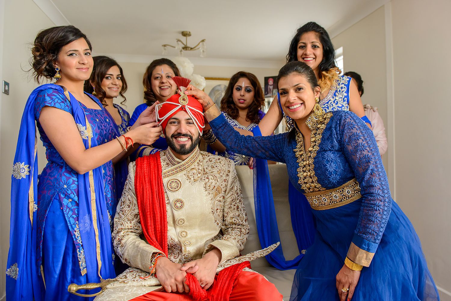Wedding party wearing vibrant blue and gold outfits posing together indoors.