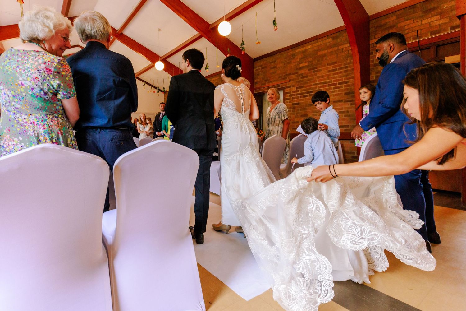 Wedding guests dance and celebrate together on a wooden dance floor at an indoor reception venue.