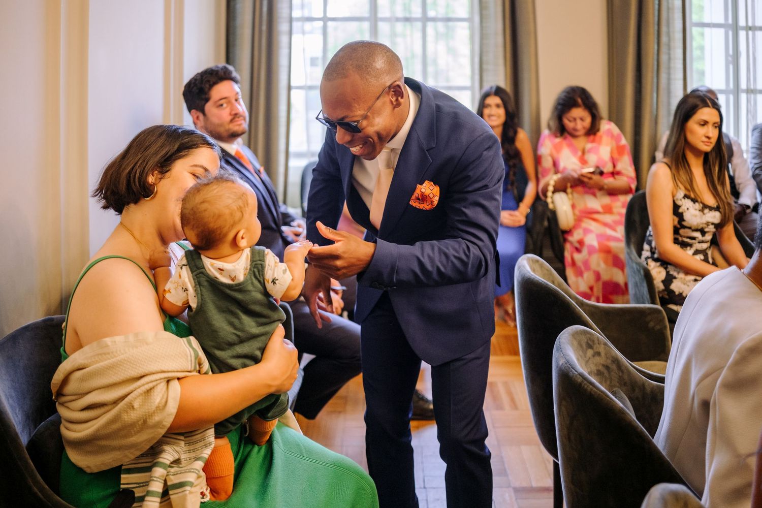 A couple celebrates their wedding day with guests in a bright indoor venue as they dance together.