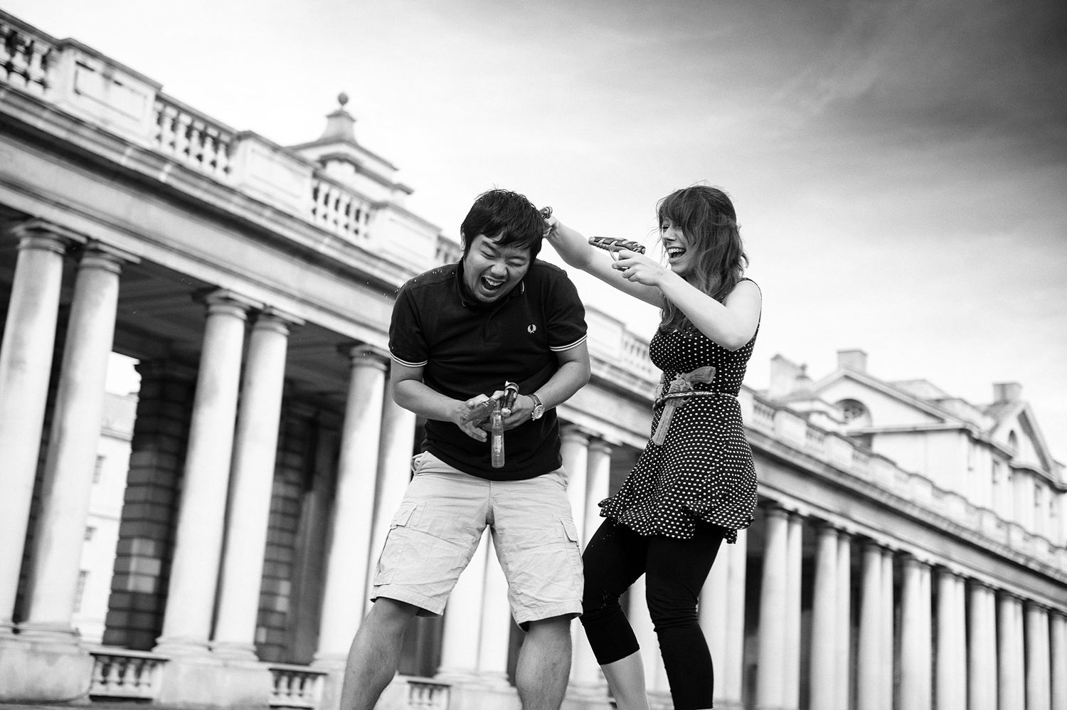 Two people share a playful moment in front of a grand historic building with columns.