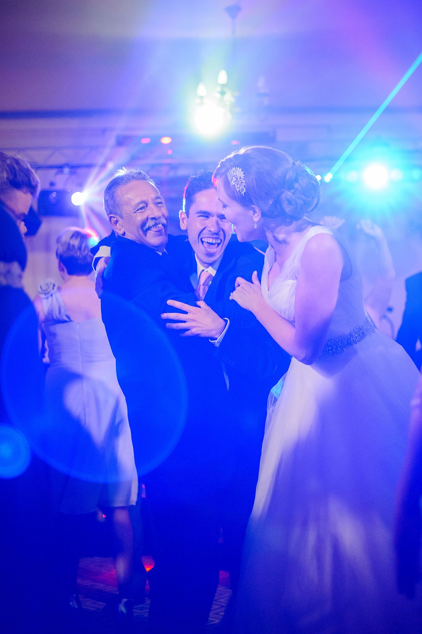 People celebrating at a wedding reception with vibrant blue lighting effects.