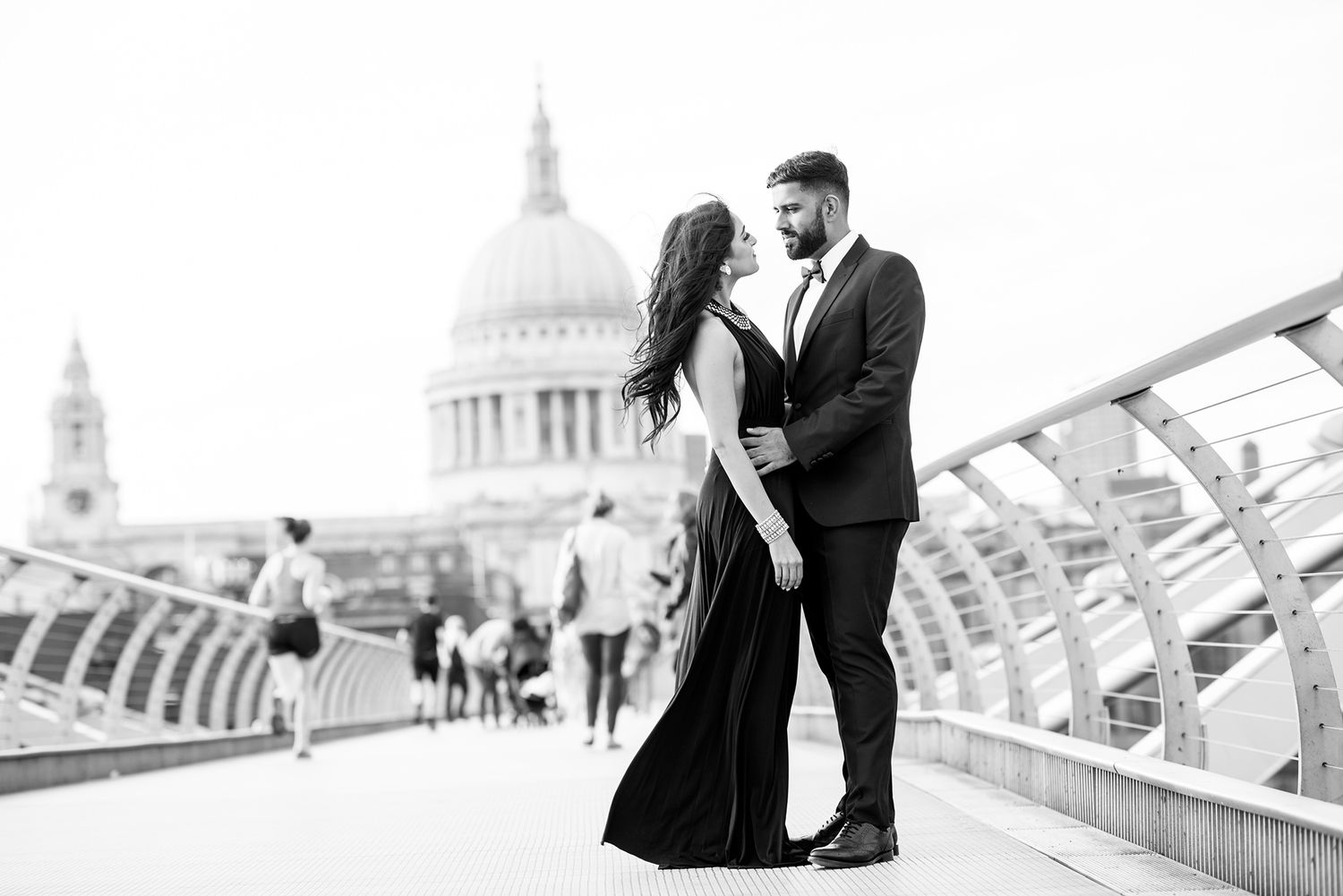 Romantic couple embracing on Millennium Bridge with St Paul's Cathedral in background.